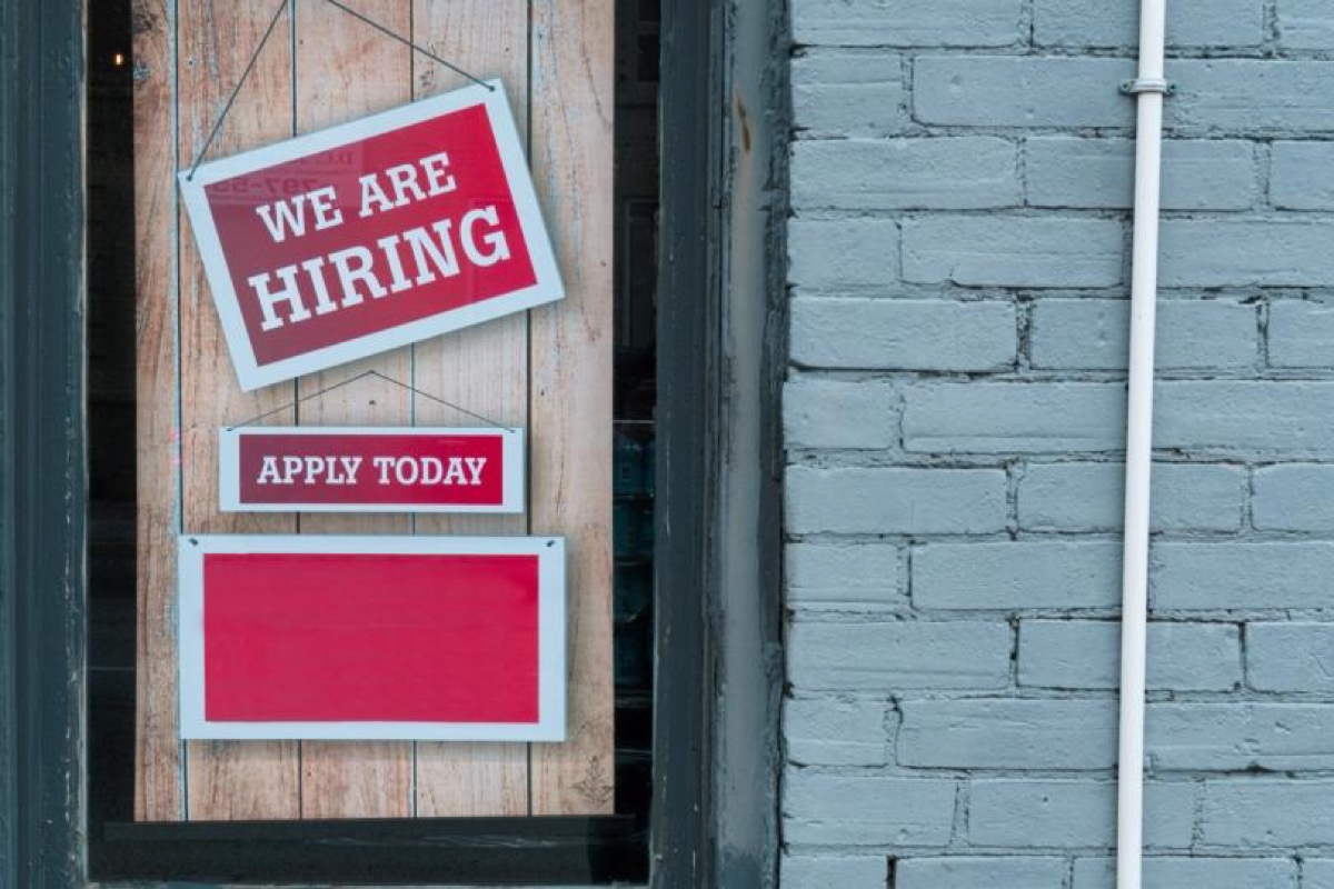 Hiring signs hang in a storefront window. Source: CoinDesk
