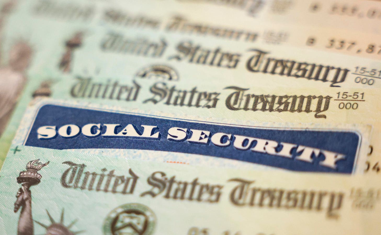 A Social Security card resting on U.S. currency alongside a monthly benefit statement, illustrating retiree income at risk