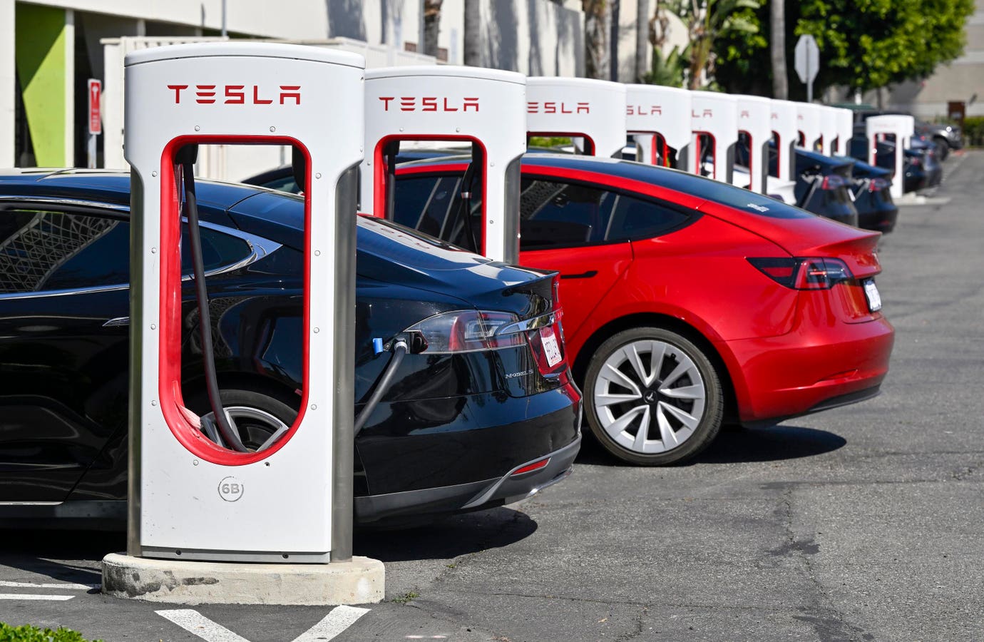 A Tesla electric vehicle at a delivery center as a stock ticker shows shares falling after Q2 2026 delivery results