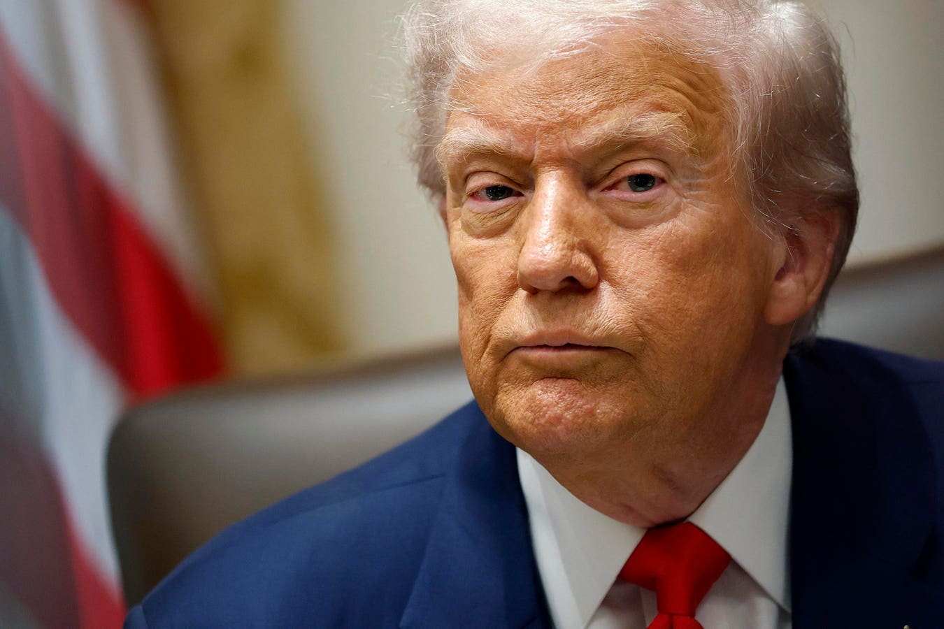President Donald Trump speaking at a podium as reporters review pages of his 2025 federal financial disclosure