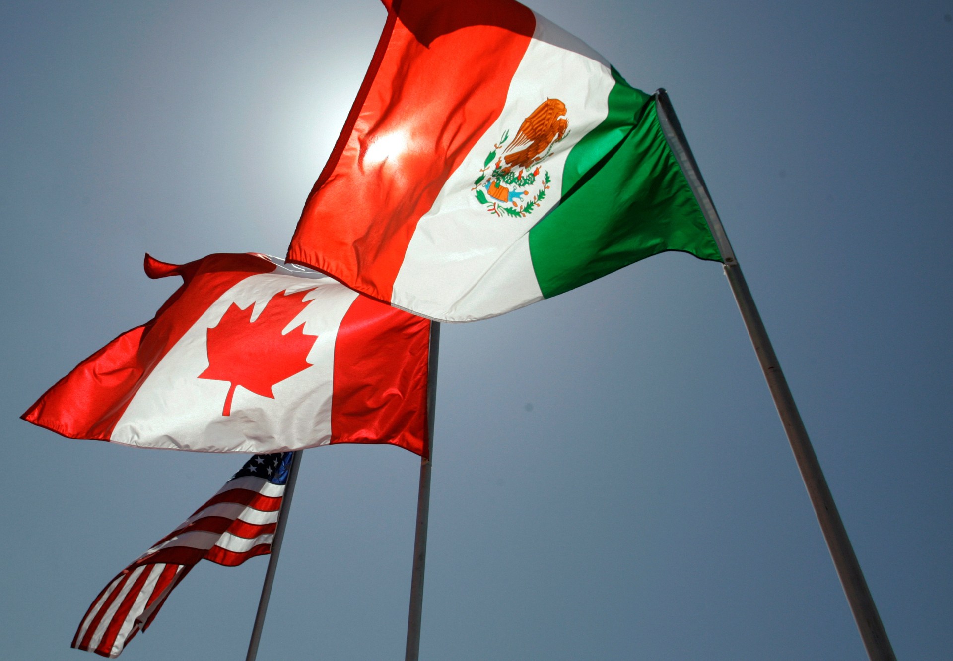 Shipping containers and trucks crossing a North American border trade checkpoint amid USMCA negotiations