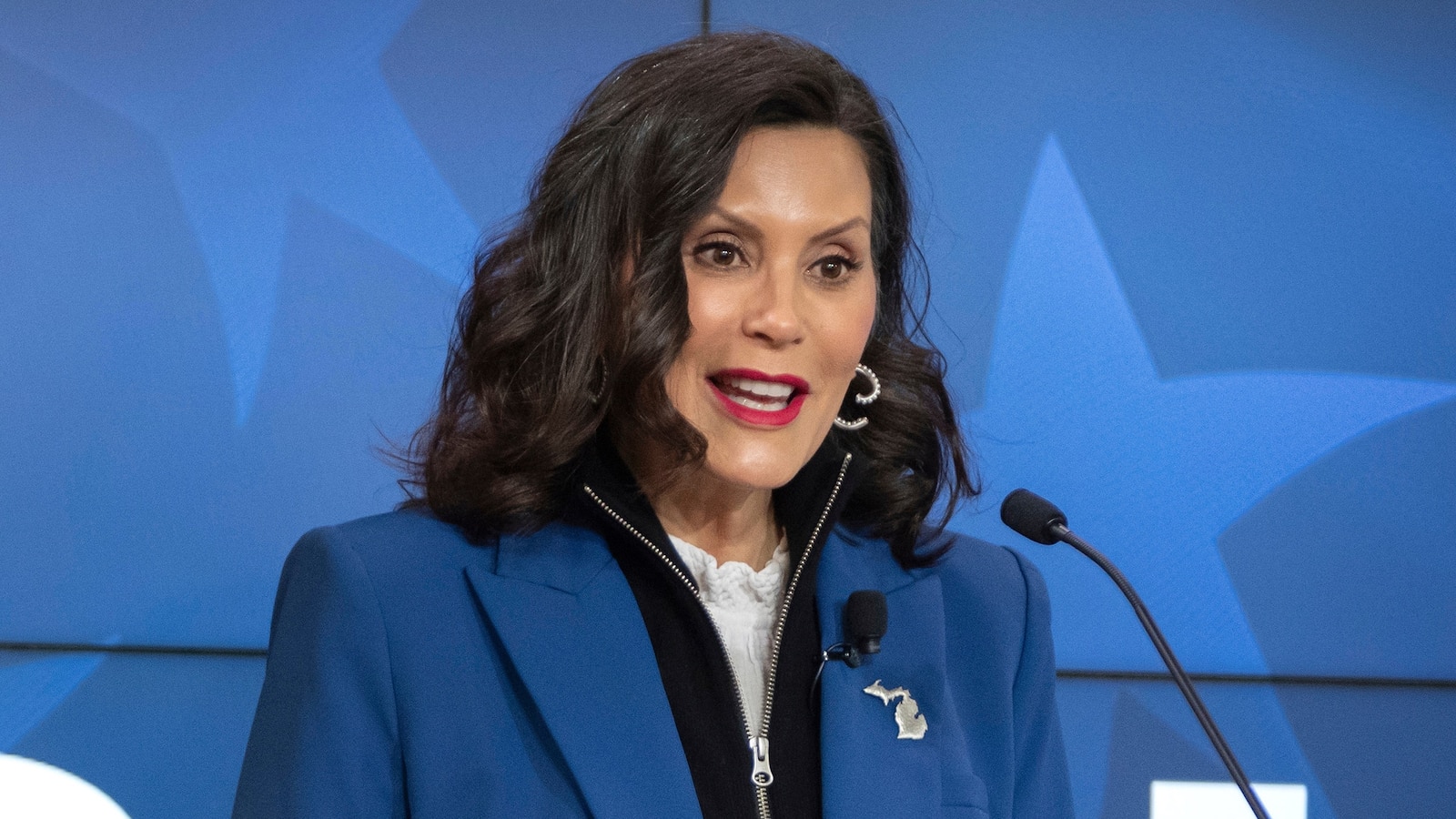 Michigan Governor Gretchen Whitmer speaking at a podium about National Guard troops deployed in Washington DC